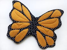 a yellow and black butterfly with polka dots on it's wings is sitting on a white surface