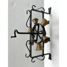 a metal clock with bells hanging from it's sides on a white wall next to a door