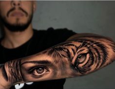 a man with a tiger eye tattoo on his arm and hand is looking at the camera