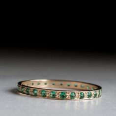 Gold eternity ring set with real Emeralds Indulge yourself in Elegance and beauty with this dainty gold ring. Perfect for stacking on worn to be worn solo. Exclusively set with Top Quality Emeralds. These Gem Stones are top notch and look exquisite under close inspection. Other stone requests and arrangements are welcome! Stone count is subject to Ring size, most rings will have between 25-30 stones. The ring width is: 2.2mm / 0.08 inches Stones are 1.5mm each. Please choose ring size on the sid Elegant Green Stackable Eternity Band, Stackable Emerald Eternity Band Gift, Stackable Emerald Eternity Band As Gift, Adjustable Stackable Emerald Wedding Ring, Gold Stackable Rings With Emeralds, Emerald Eternity Ring, Gold Eternity Ring, Eternity Ring Set, Dainty Gold Ring