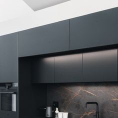 a kitchen with black cabinets and marble counter tops