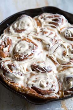 a pan filled with cinnamon rolls covered in icing