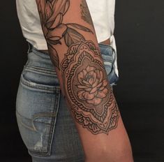 a woman's arm with a flower tattoo on the left side of her arm