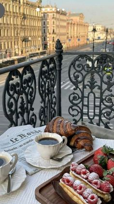 two trays filled with pastries on top of a table next to a cup of coffee