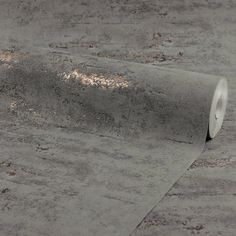 a roll of toilet paper sitting on top of a cement floor next to a wall