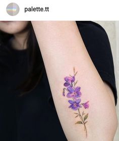 a woman with a tattoo on her arm has a purple flower tattooed on it's left arm