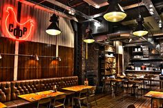 the interior of a restaurant with wooden tables and leather booths, hanging lights, and exposed brick walls