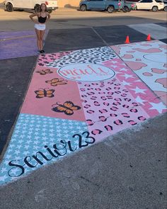 a woman standing on the side of a parking lot next to a painted area with butterflies