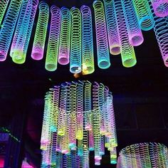 colorful lights hanging from the ceiling in a dark room with many tubes attached to it