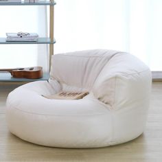 a white bean bag chair sitting on top of a hard wood floor next to a book shelf