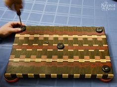 a person is using a tool to make a wooden board with circles and squares on it