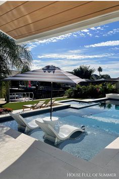 an umbrella and chair sitting on the side of a swimming pool in front of a house