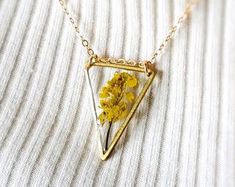 a necklace with a yellow flower in the shape of a triangle on a gold chain