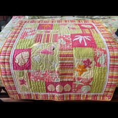 a quilted bed with pink, green and yellow colors