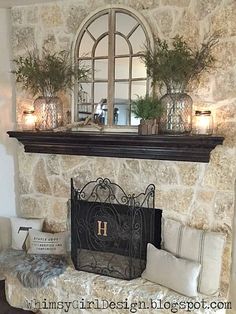 a stone fireplace with candles and plants on the mantel above it in a living room