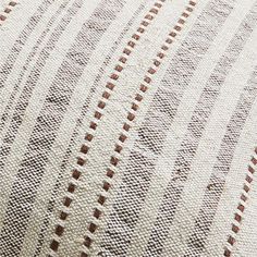 an upholstered white and brown pillow with stripes on it's side, closeup