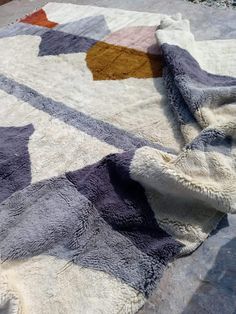 a patchwork rug is laying on the ground with it's edge partially covered by a blanket