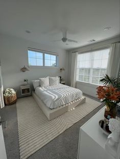 a large white bed sitting in the middle of a bedroom next to a tall window