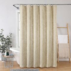 a white bath tub sitting next to a shower curtain in a bathroom on top of a wooden floor