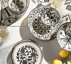 black and white plates with designs on them sitting on a table next to lemons