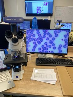 a microscope and two laptops on a desk with computers in front of them,