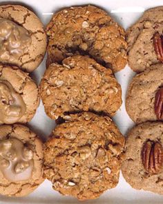 several cookies with pecans and nuts in a white box on a table top, ready to be eaten