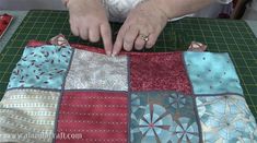 a woman is working on some quilts at a table with scissors and sewing needles