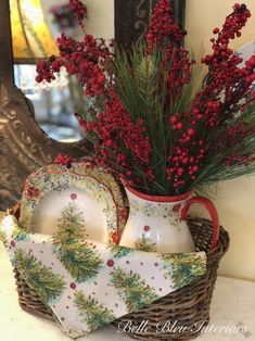 a basket filled with red berries and greenery on top of a counter next to a mirror