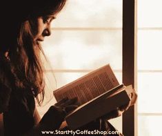 a woman is reading a book in the dark, with sunlight coming through her window