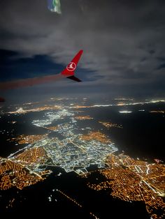 an airplane flying over the city lights at night