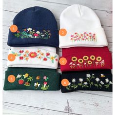 four beanies with embroidered flowers and numbers on the side, all in different colors