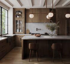 a large kitchen with wooden cabinets and counter tops, along with two bar stools