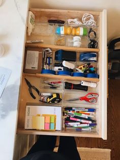 an open drawer filled with office supplies on top of a table