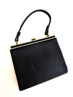 A classic 60s black nylon kiss lock top handle hand bag. Simple yet elegant purse with clean lines and bright gold tone trim. Ships USA, fast free shipping. Measures approx. 6"x8" Nice clean vintage condition no smells or stains  Please see additional pics for more details and measurements  Shipping includes tracking and insurance  thejewelrycabinet.etsy.com www.instagram.com/thejewelrycabinet  www.fb.com/thejewelrycabinet Small Black Purse, Silver Springs, Bright Gold, Black Purses, Black Nylons, Top Handle, Gold Trim, Beautiful Quilts, Vintage Black