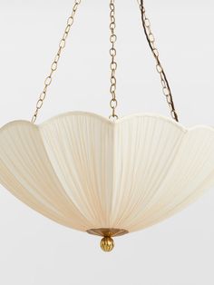 a chandelier hanging from the ceiling with white pleated fabric and gold chains