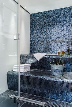 a bathroom with blue tiles on the walls, and a bathtub in the middle