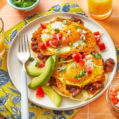 two breakfast tacos on a plate with avocado and tomatoes