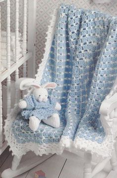 a white rocking chair with a blue crocheted blanket and a stuffed bunny on it