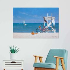 a bicycle parked on the beach next to a lifeguard tower with sailboats in the background