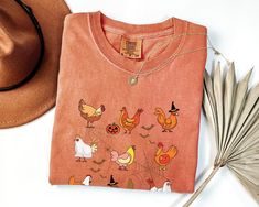 an orange t - shirt with chickens and pumpkins on it next to a fan