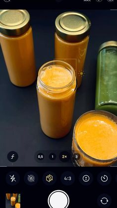 three jars filled with orange liquid next to each other