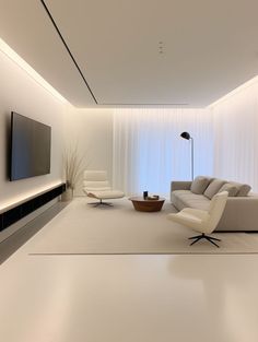 a living room with white furniture and a flat screen tv mounted on the wall above it