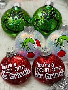 three christmas ornaments with grin on them and one saying you're a mean one