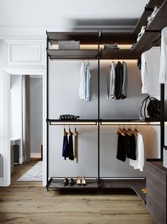 an open closet with clothes and shoes hanging on the shelves, along with other items