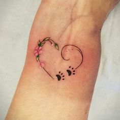 a small tattoo on the wrist of a woman's left arm with a dog paw and flower