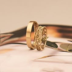 two gold wedding bands sitting on top of each other