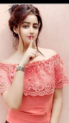 a young woman posing for the camera with her finger on her lips and wearing a pink top