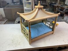 a dollhouse made out of wood with a blue pillow in the bottom bunk bed