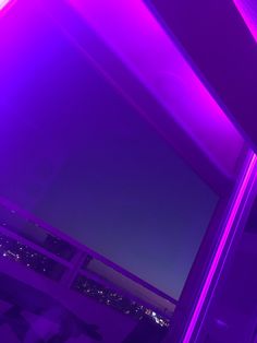 a window with purple lights on it and a view of the city at night in the distance