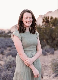 a woman standing in the desert with her hands on her hips and smiling at the camera